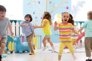 Group of happy children of boys and girls run in day care. Kids play in kindergarten