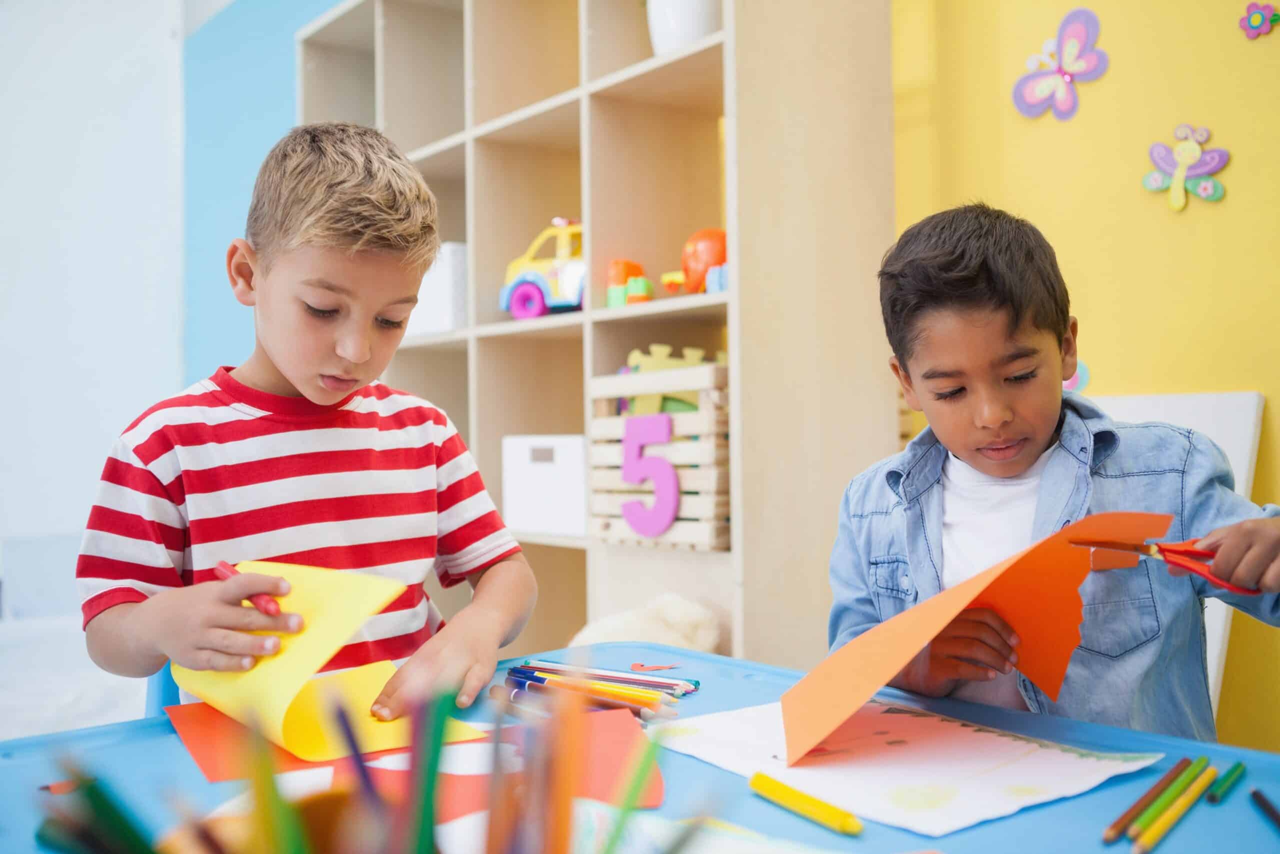 boys cutting paper shapes in classroom