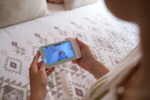 mother watching the baby from the monitor of the camera baby monitor from the bed of her room